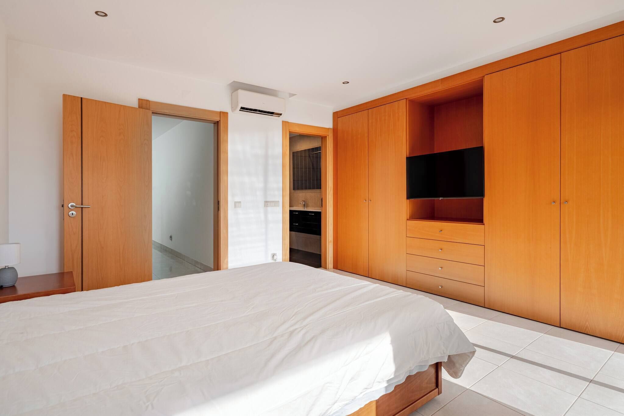 Ein Schlafzimmer mit Bett, Kleiderschrank und einer integrierten TV-Konsole.
