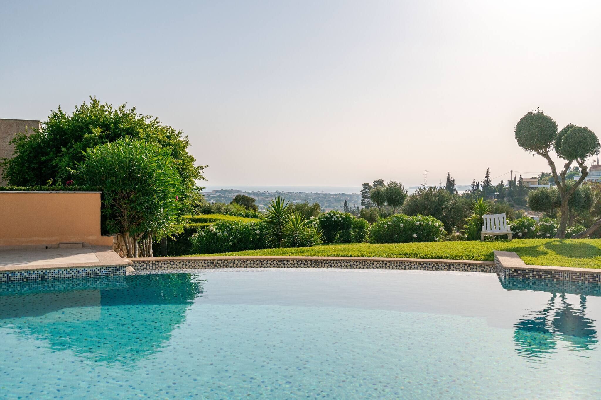 A swimming pool with a clear view of the surrounding landscape and distant cityscape.