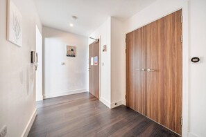 A hallway with wooden flooring, a double door, and a wall-mounted intercom. - Spacious Wimbledon Flat Walk to Staton Sleeps 4 (London)