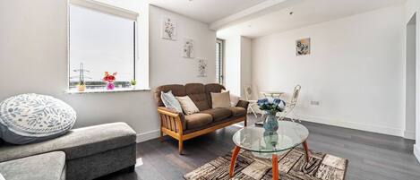 A modern living room with a sofa, ottoman, and glass coffee table.