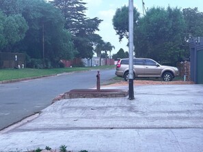 A residential street with a parked SUV, a sidewalk, and a utility pole.
