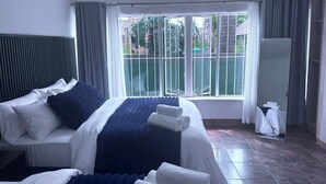 Una camera d'albergo con un letto grande, una finestra vista verde e uno specchio.