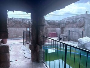 Un recinto exterior con piscina, muros de piedra y cerramiento de metal.