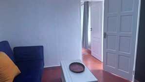 A room with a blue sofa, a white side table with a pie on it, and a closed white door.