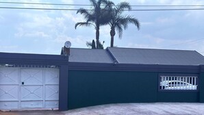 A building with a garage door, a satellite dish, and a palm tree in the background.