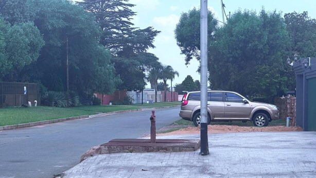 A residential street with a parked SUV, a sidewalk, and a utility pole.