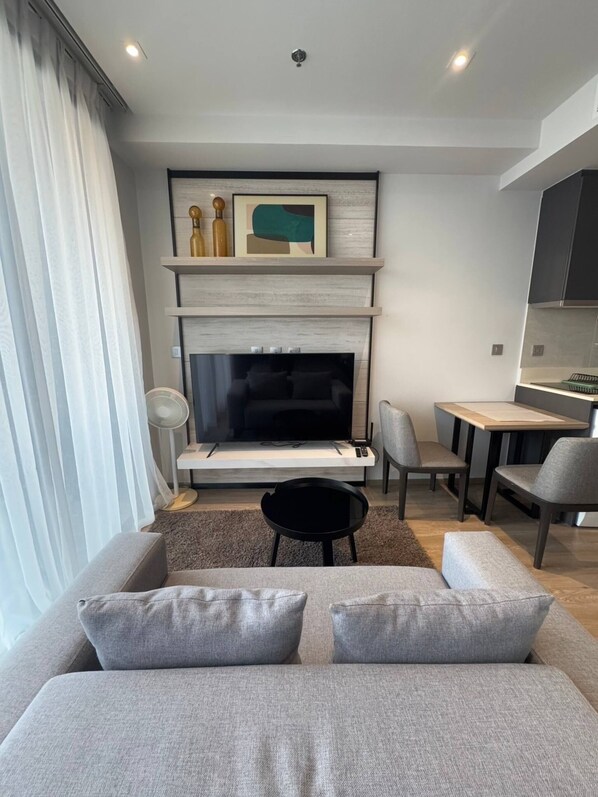 Ein modernes Wohnzimmer mit Sofa, Fernseher und Essbereich.