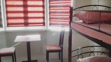 A room with bunk beds, a desk, a chair, and a TV mounted on the wall.