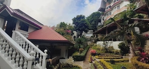 A residential area with a staircase leading to a red-roofed building, surrounded by lush greenery and a well-maintained garden. - Avana Hills Boracay Prime - Horizon 2 (Malay)