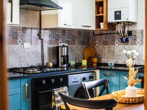 A kitchen with a gas stove, coffee maker, microwave, and a washing machine. - Charming 3-Bedroom Apartment in Historic Carthage, Tunisia (Site archéologique de Carthage)