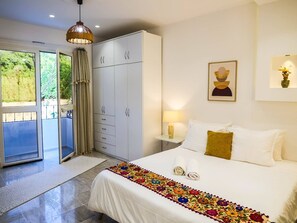 A bedroom with a bed, a wardrobe, a nightstand, a lamp, and a painting. - Charming 3-Bedroom Apartment in Historic Carthage, Tunisia (Site archéologique de Carthage)