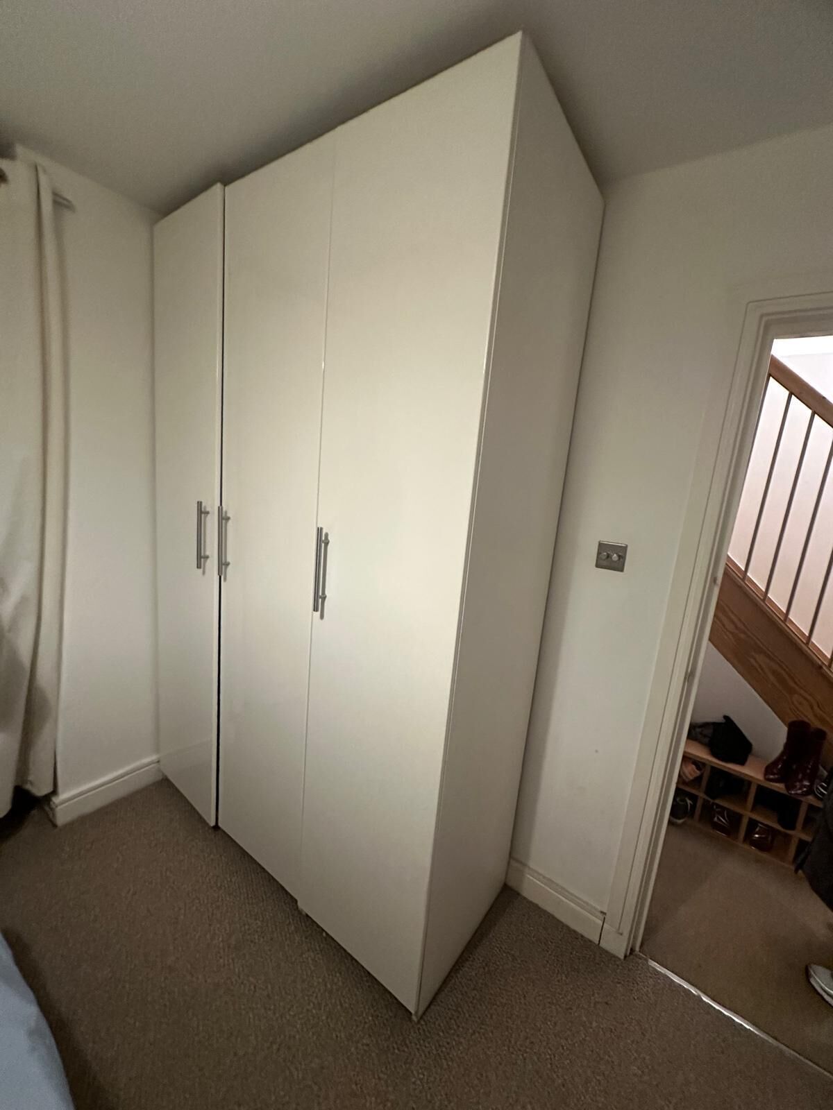 Une pièce dotée d’une grande armoire blanche, d’une porte donnant sur un escalier et d’un plancher recouvert de moquette.