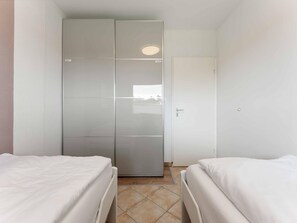 Ein Hotelzimmer mit zwei Betten, einem Kleiderschrank und einer Tür.