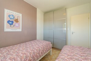 Ein Schlafzimmer mit zwei Betten, einem Kleiderschrank und einem gerahmten Bild an der Wand.