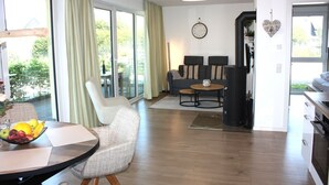 En moderne stue med en sofa, et sofabord og et spiseområde med et bord og stole.