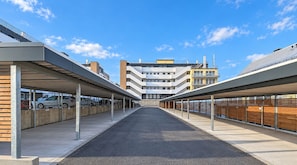 Un'area di parcheggio coperta con diversi livelli, un percorso centrale e un edificio sullo sfondo.