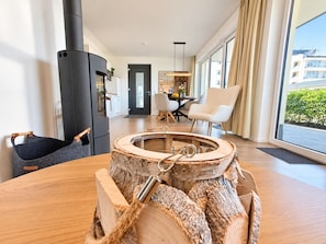 A modern living room with a large wooden table, a black fireplace, and a dining area with chairs and a table. - Vacation Rental with Infrared Sauna, Fireplace, and Terrace in Winterberg - Mountain Resort (Winterberg)
