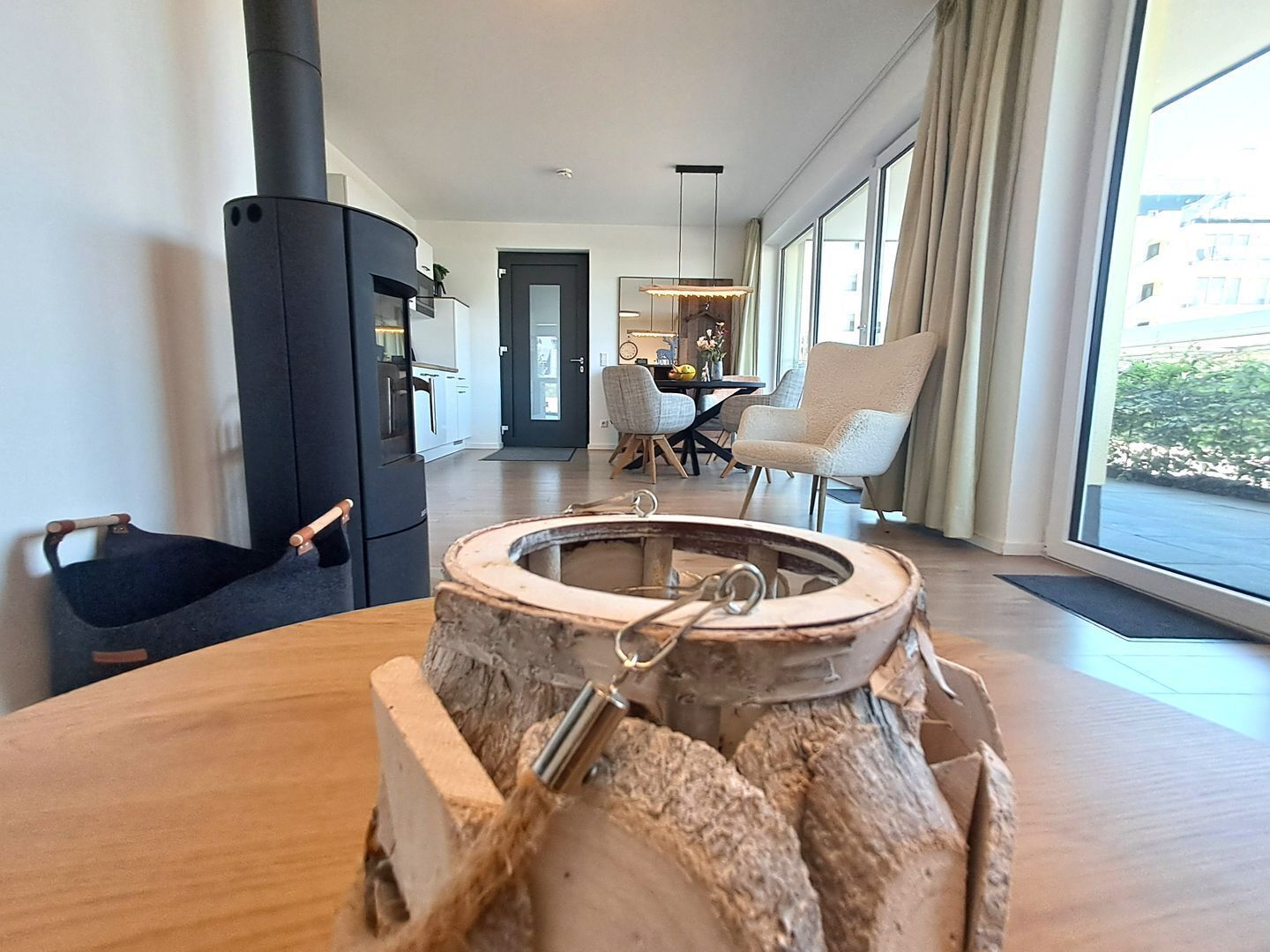 Una sala de estar moderna con un ventanal grande, una chimenea y un comedor al fondo.