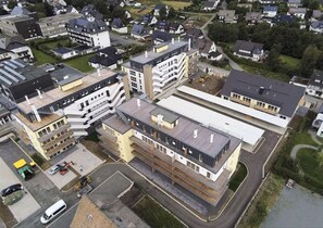 Ein modernes, mehrgeschossiges Gebäude mit einer Mischung aus Wohn- und Gewerbeflächen, das einen Innenhof und einen Parkplatz bietet.
