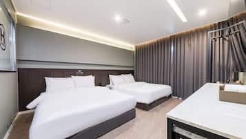 Habitación de hotel con dos camas, un escritorio y un ventanal con cortinas.