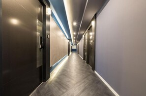 A modern hotel corridor with a long, straight path, doors on both sides, and a ceiling with recessed lighting. - Hotel Harbor (Tongyeong)