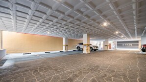 A parking garage with a patterned ceiling, concrete pillars, and a paved floor. - Hotel Harbor (Tongyeong)