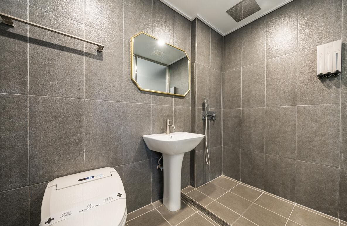 A bathroom with a white sink, a mirror, and a toilet.