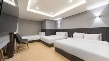 Een hotelkamer met drie bedden, een bureau en een stoel.