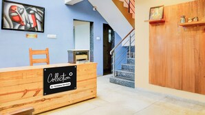 Un comptoir d’accueil avec un panneau indiquant qu’il s’agit d’un point de collecte desservi par l’entreprise, un escalier et un espace d’accueil agrémenté d’un tableau au mur.