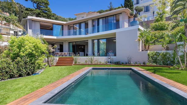 Uma casa moderna de dois andares com piscina, varanda coberta e um jardim bem cuidado.