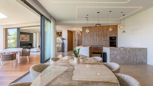 Cozinha moderna com bancada de mármore, armários de madeira e iluminação pendente.