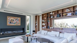 Uma sala de estar moderna com um sofá modular, uma lareira e uma estante repleta de livros e objetos decorativos.