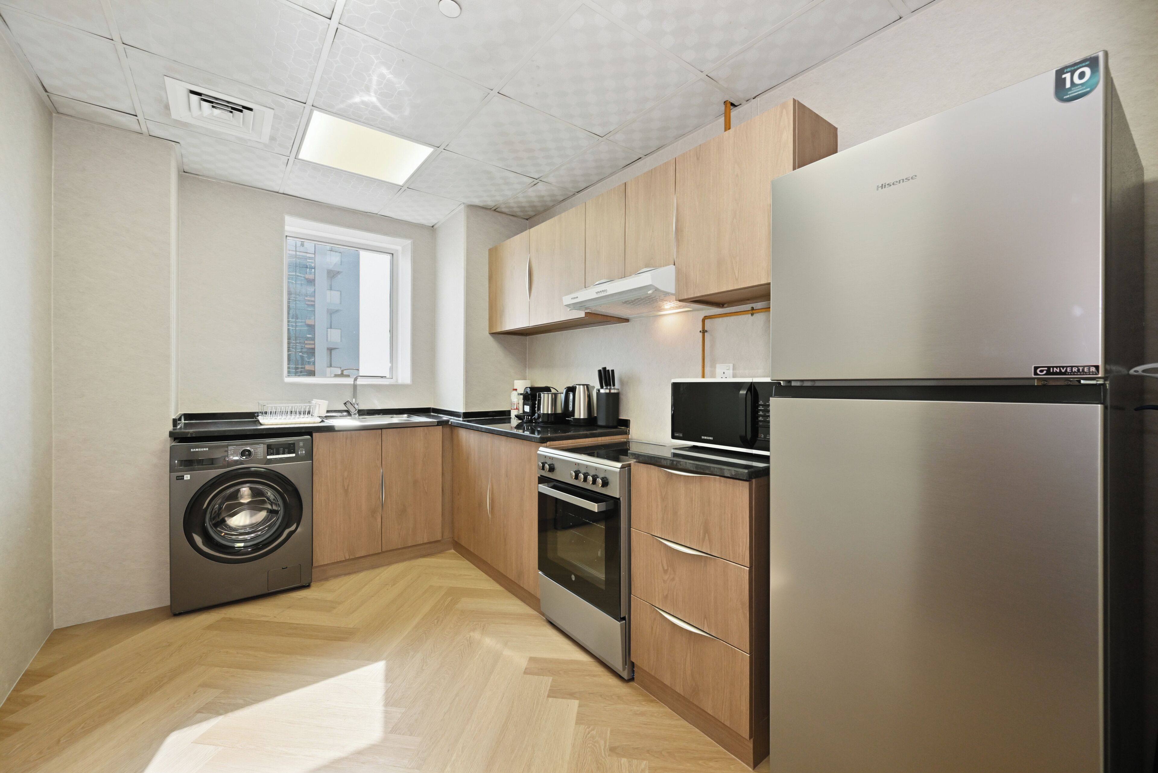 Une cuisine moderne dotée d’appareils électroménagers en acier inoxydable, de meubles en bois et d’un lave-linge encastré.