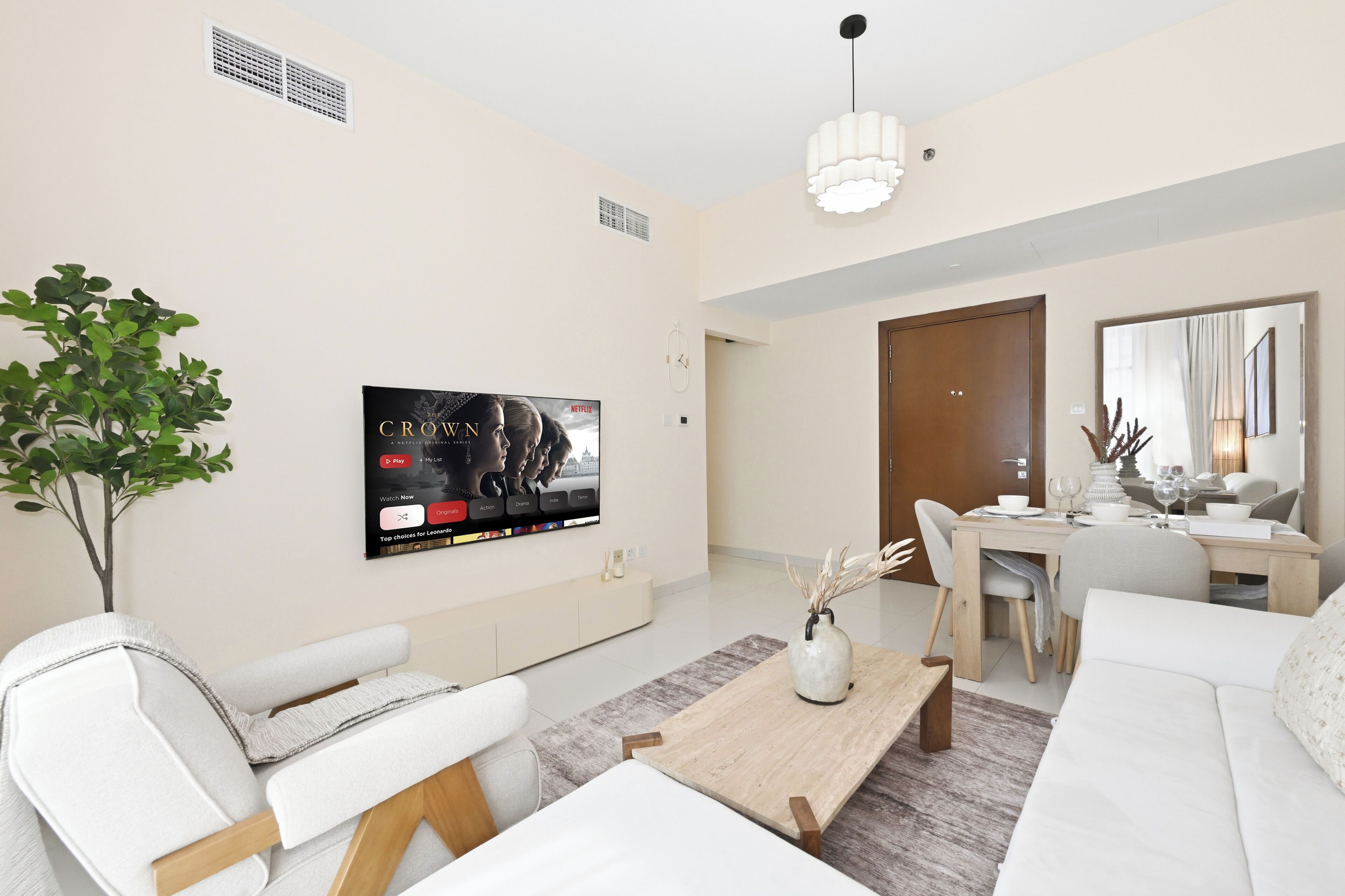 Una sala moderna con un televisor de pantalla plana montado en la pared, un comedor con mesa y sillas, y un ventanal grande.