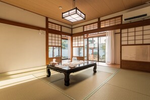 A traditional Japanese room with tatami flooring, a low table with a tissue box, and a hanging light fixture. - Private Japanese Garden House Near KIX Osaka | 6BR for 6-12 guests | Hinoki Bath (Kumatori)