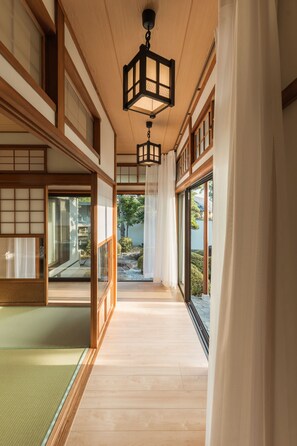 A traditional Japanese interior with sliding doors, wooden flooring, and a hanging lantern. - Private Japanese Garden House Near KIX Osaka | 6BR for 6-12 guests | Hinoki Bath (Kumatori)