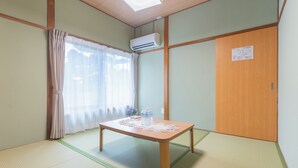A room with tatami flooring, a wooden table with a water bottle, and a sliding door.
