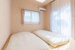 A room with two beds, a window with curtains, and an air conditioning unit. - Private Japanese Garden House Near KIX Osaka | 6BR for 6-12 guests | Hinoki Bath (Kumatori)