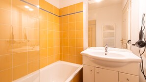 Un baño con una bañera blanca, un lavabo blanco y un espejo sobre el lavabo.