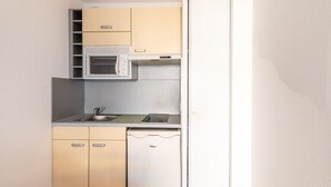 Una cocina compacta con microondas, lavamanos y armarios.