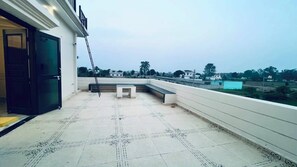 A rooftop terrace with a bench, a ladder, and a view of the surrounding area. - Mannat Villa (Ramnagar)