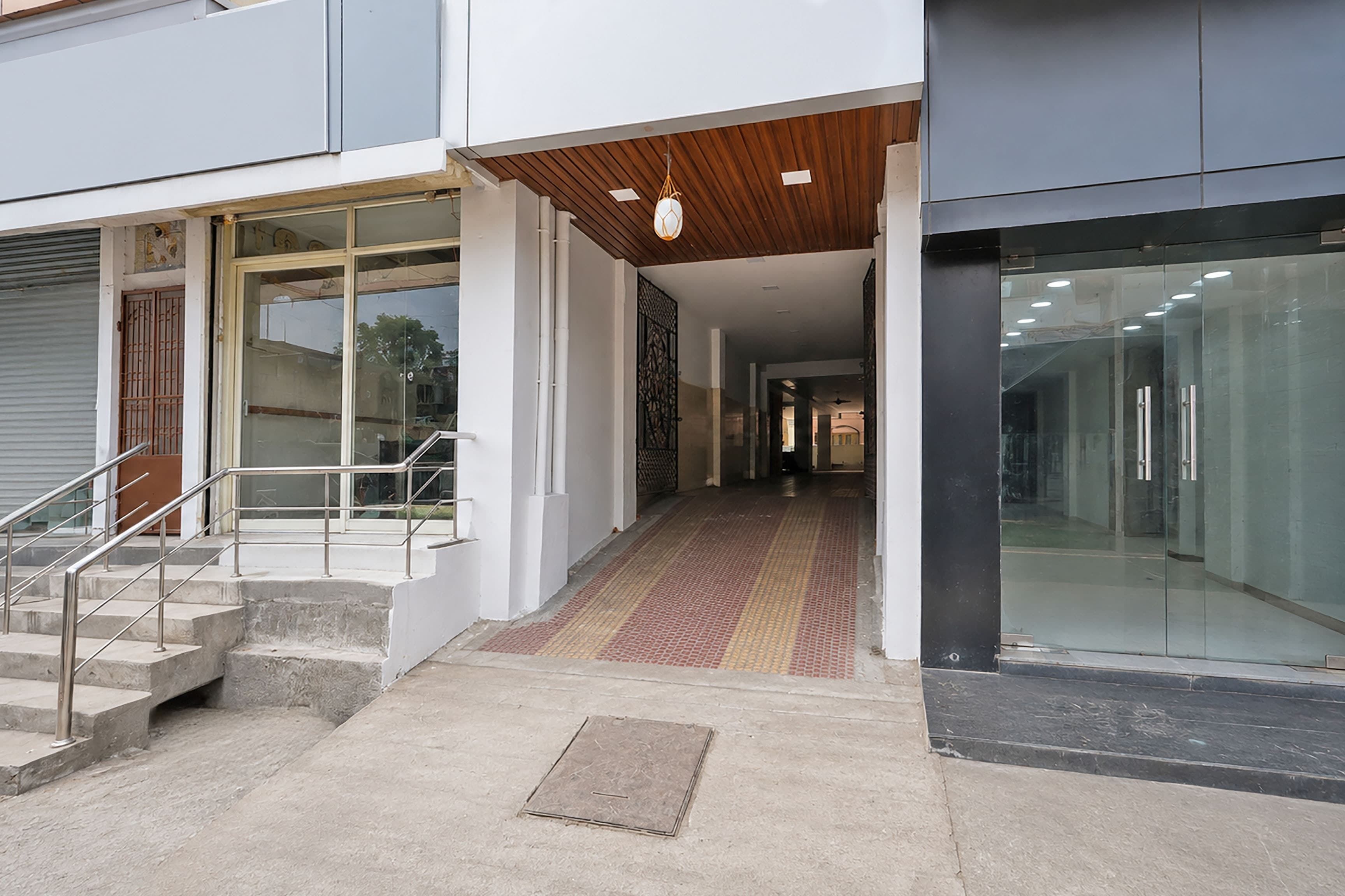 A modern building entrance with a ramp, glass doors, and a staircase.