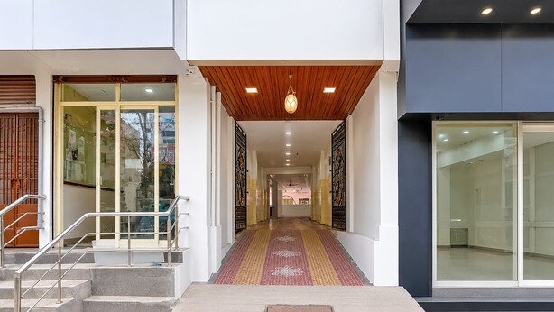 A modern building entrance with a ramp leading to a staircase, a patterned carpet, and a metal handrail.
