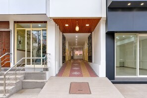 A modern building entrance with a ramp leading to a staircase, a patterned carpet, and a metal handrail. - Super Collection O Rajahmundry Pushkar (Rajahmundry)