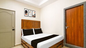 A bedroom with a wooden bed, a door, and a wall with three framed pictures.