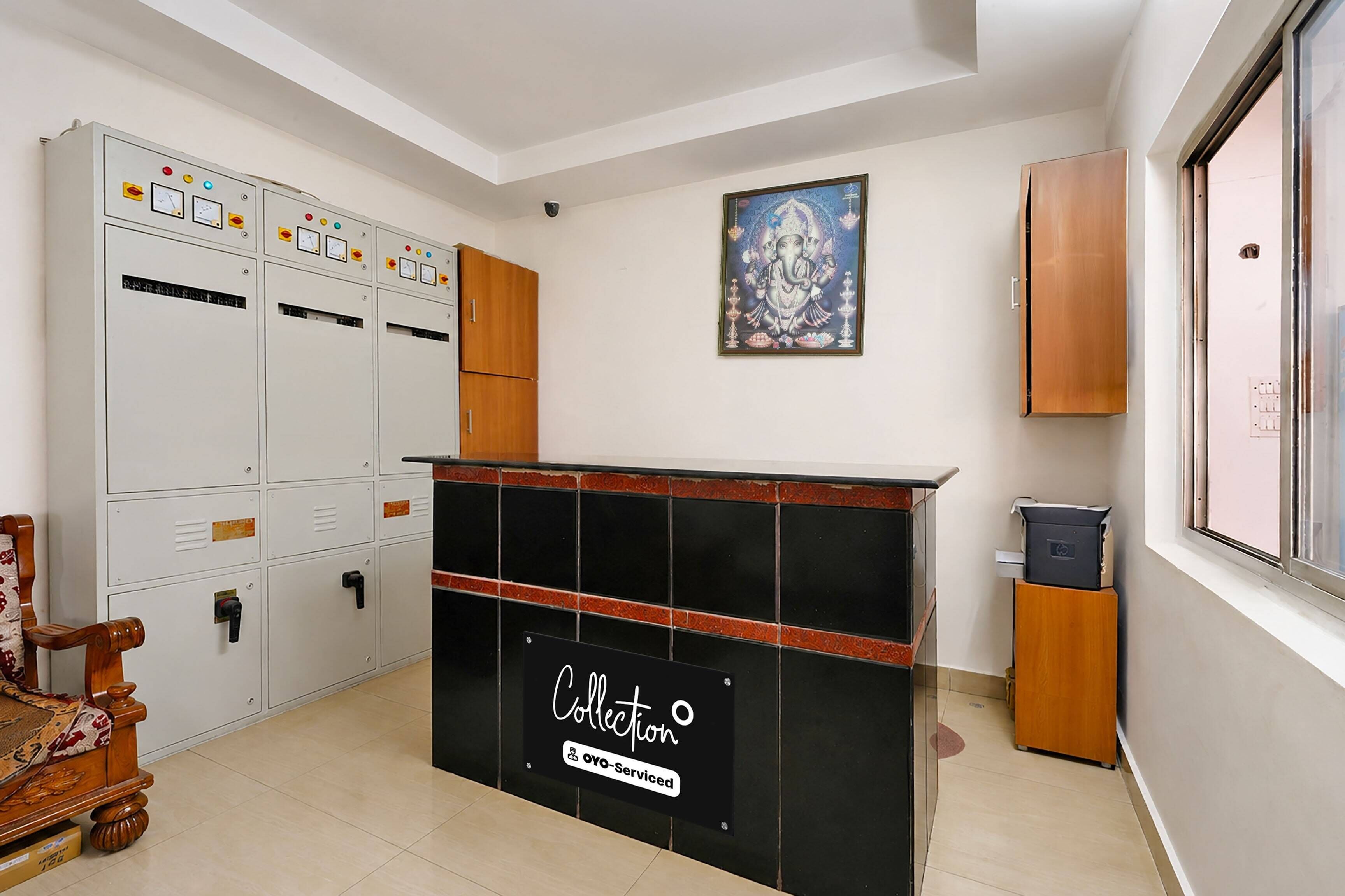 A reception area with a black counter, a framed religious painting, and a wooden cabinet.
