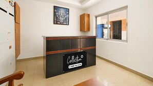 A hotel reception area with a black counter, a framed picture above it, and a window with a view of the outside.