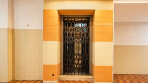 A hallway with a patterned floor, a metal gate, and a tiled wall.