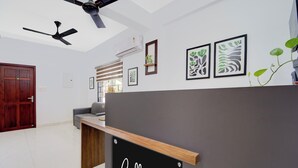 A modern interior with a grey partition, ceiling fans, and framed artwork on the walls. - Super Collection O Valiyavila Junction (Thiruvananthapuram)