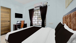A hotel room with a bed, a desk, a chair, a TV, and a window with curtains. - Super Collection O Valiyavila Junction (Thiruvananthapuram)